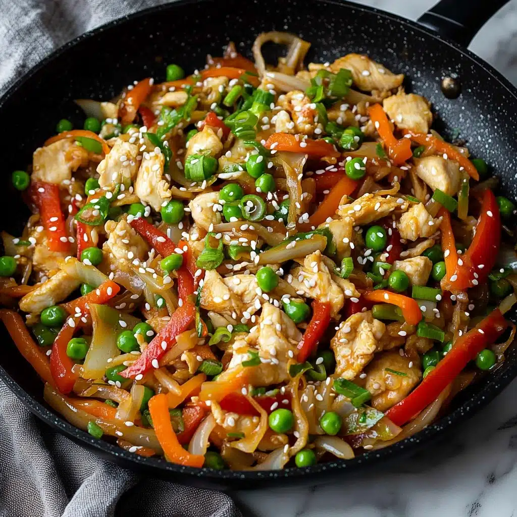 Chicken and Cabbage Stir Fry, healthy chicken stir fry, quick weeknight dinner, easy cabbage stir fry, nutritious vegetable chicken dish The image shows a white bowl filled with a colorful stir-fry dish placed on a white marbled surface. Inside the bowl, there are visible layers including bright green peas, light orange carrot strips, soft golden tan chicken pieces, translucent white onion slices, and red bell pepper slices, all mixed together and sprinkled with white sesame seeds and chopped green onions on top. Black chopsticks are placed inside the bowl, touching the food. Next to the bowl is a black pan containing more of the same stir-fry mix with peas, onions, carrots, and chicken. The overall texture of the food is glossy and fresh.