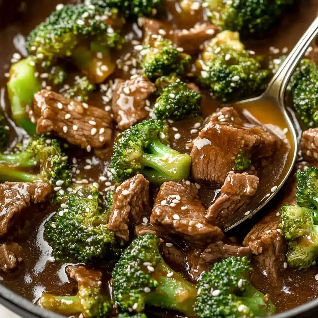 Chinese Beef and Broccoli, Chinese Beef and Broccoli recipe, homemade Chinese beef and broccoli, easy beef and broccoli stir-fry, takeout-style Chinese beef and broccoli A close-up view of a dish with layers of green broccoli florets and dark brown pieces of beef mixed together in a thick, glossy brown sauce. The dish is sprinkled with small white sesame seeds, adding texture on top. A metal spoon is partially shown in the mix, scooping some broccoli and beef. The background features a white marbled texture.