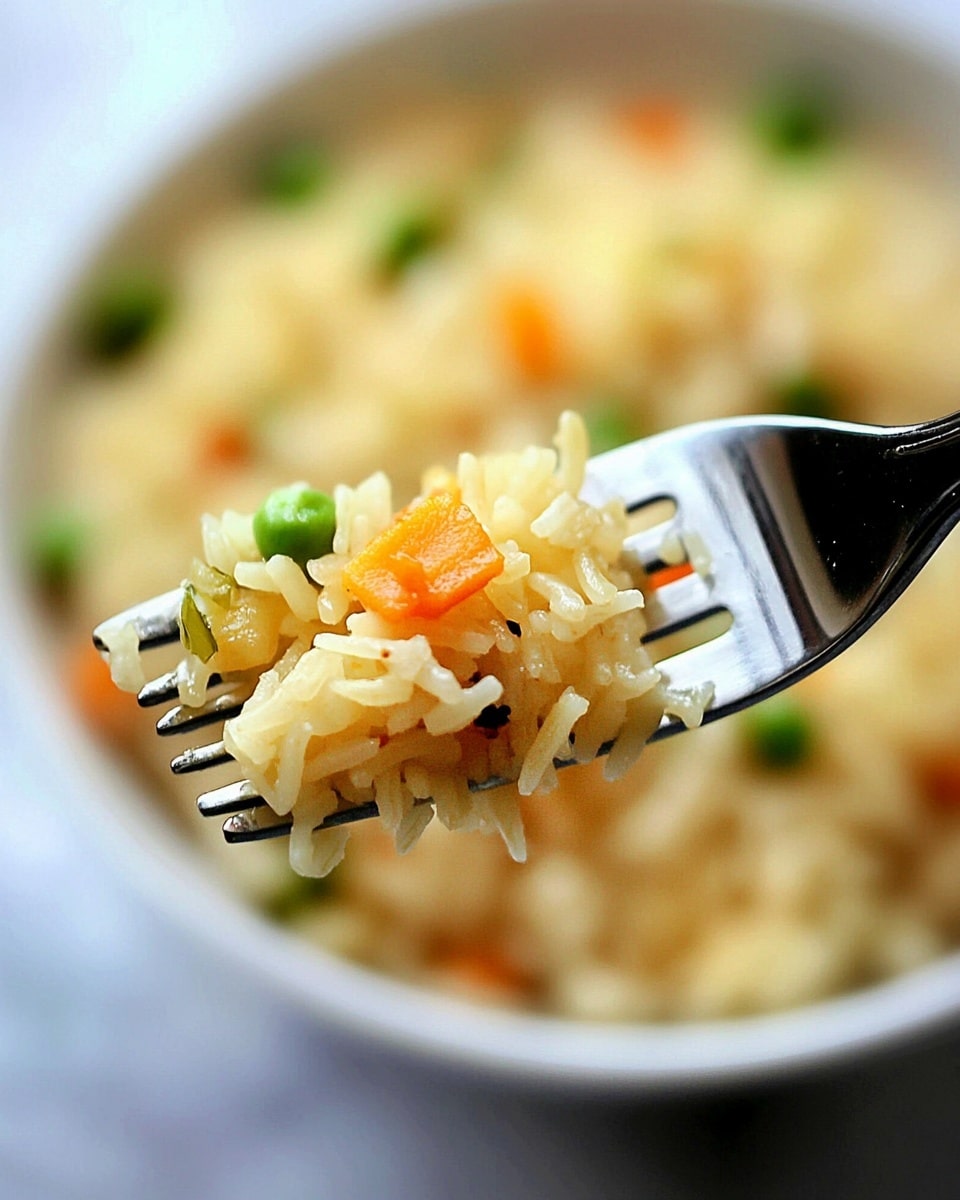 A close-up view of a silver fork holding a bite of cooked yellowish rice mixed with small pieces of orange carrot and green peas, with some blurred background that seems to be more rice in a white bowl, all set on a white marbled surface. photo taken with an iphone --ar 4:5 --v 6.1