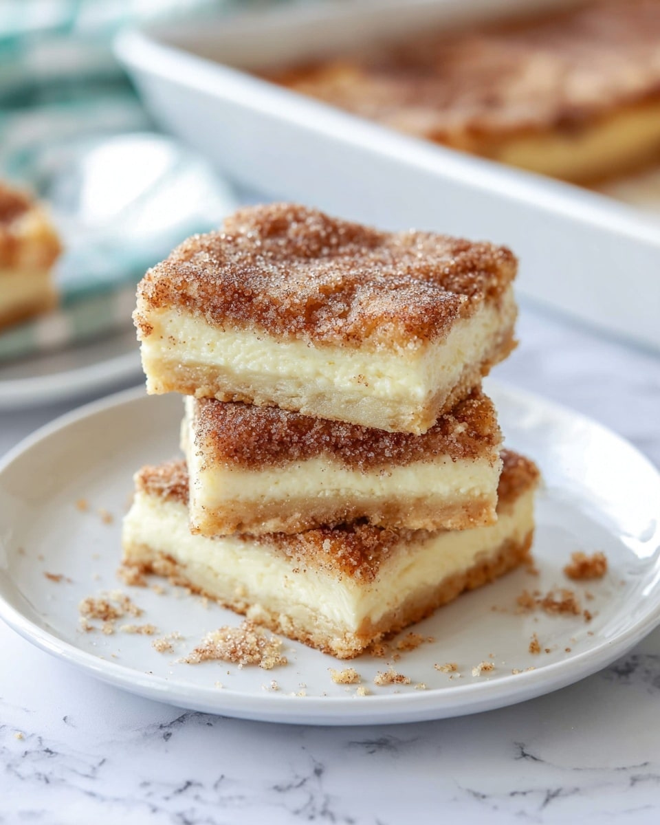 The image shows three square pieces of a layered dessert stacked on a white plate, placed on a white marbled surface. Each piece has three visible layers: a golden-brown bottom crust, a thick creamy light-yellow middle layer, and a top layer covered with a textured light brown topping sprinkled with sugar crystals and cinnamon. The edges look soft but slightly firm, and crumbs are scattered around the plate's base. In the blurred background, part of a white baking dish with more of the dessert inside is visible. Photo taken with an iphone --ar 4:5 --v 7