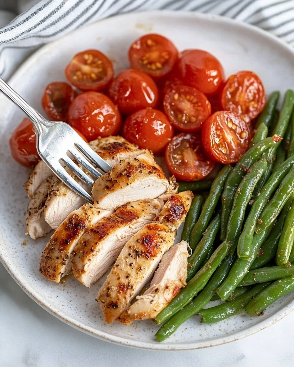 A white rectangular baking dish holds four cooked chicken pieces arranged in two rows of two. The chicken pieces have a golden brown surface with visible herbs and small bits of seasoning. Around and partially on top of the chicken, there are many bright red cherry tomatoes, some whole and some sliced in half, softened and mixed with a shiny brown sauce. The dish sits on a white marbled surface. photo taken with an iphone --ar 4:5 --v 6.1