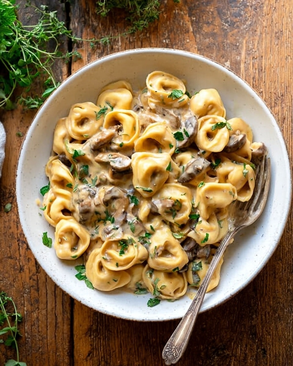 The image shows a large white pan filled with creamy pasta shells covered in a rich light brown sauce mixed with small pieces of cooked meat. The pasta looks soft and tender, and the sauce is thick and smooth. Small green herb leaves are scattered on top, adding a touch of color. A spoon is resting inside the pan, ready to serve. The pan is placed on a white marbled textured surface with a striped cloth and a glass of water nearby. Photo taken with an iphone --ar 4:5 --v 7