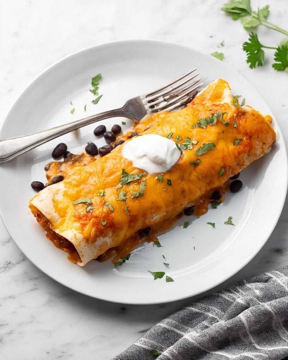 A white plate holds a single rolled enchilada covered with melted orange cheese, with small bits of green herbs sprinkled on top. There is a dollop of white sour cream on the center of the enchilada. Around the dish, a few black beans and chopped green herbs are scattered. A silver fork rests diagonally on the plate, partially behind the enchilada. The plate is set on a white marbled surface, with a gray and white striped cloth partially visible at the edge of the frame. Photo taken with an iphone --ar 4:5 --v 7