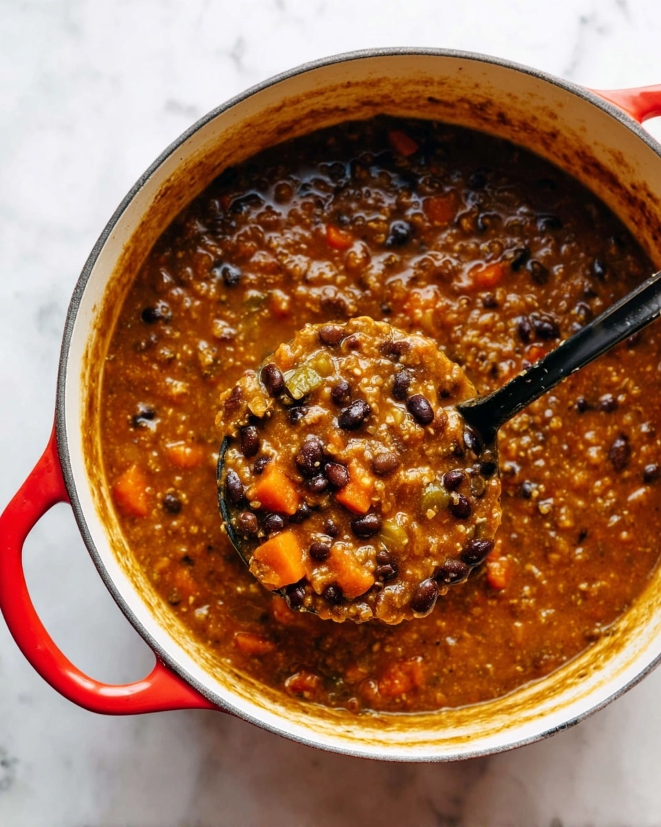 A large white pot with a red handle holds a thick stew with a brownish-orange color. The stew has many small round black beans mixed with tiny grain-like pieces and some soft chunks of orange vegetable. A black ladle is scooping some stew from the pot, showing the thick texture and mixture of ingredients. The pot is placed on a white marbled surface. Photo taken with an iphone --ar 4:5 --v 7