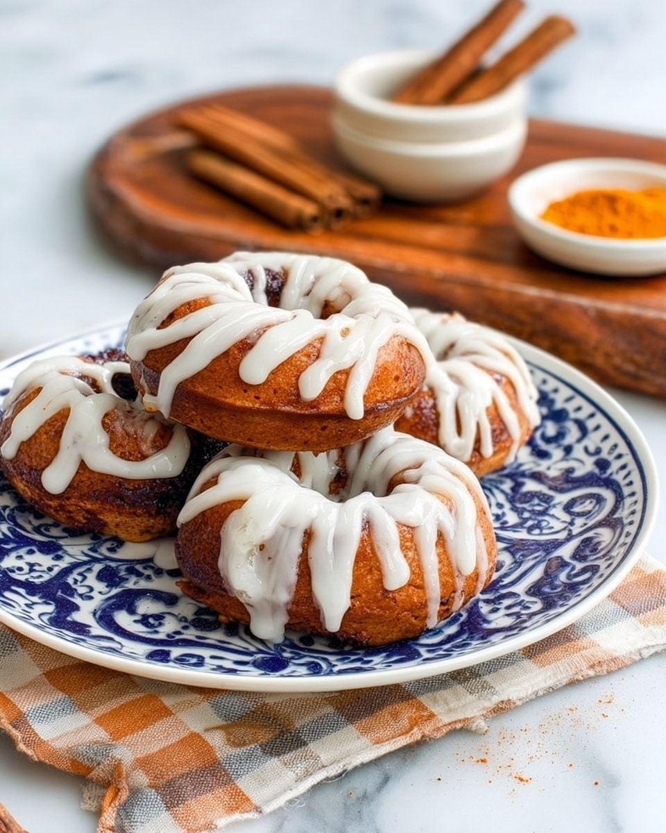 A close-up image of several brown donuts stacked on a white plate with blue floral patterns. Each donut has a thick layer of white icing drizzled in uneven stripes, dripping slightly down the sides. The donuts have a rough, crumbly texture visible under the smooth icing. The plate sits on a wooden surface with a white marbled background softly blurred behind it. The focus is on the donut in front, showing detail in the icing and donut texture. photo taken with an iphone --ar 4:5 --v 7
