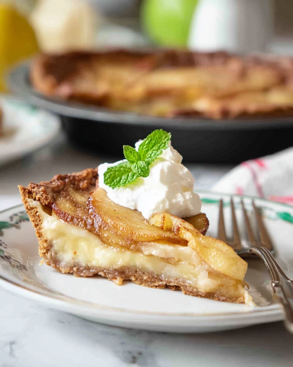 A slice of pie on a white plate showing three layers: the bottom crust is golden brown and crisp, the middle layer is a creamy, pale yellow filling with a soft texture, and the top layer has thin, caramelized slices of fruit lightly browned around the edges. A dollop of white whipped cream sits on top, garnished with a small green mint leaf. To the right of the plate, a silver fork rests on the white marbled surface. In the background, a pie with a similar golden brown top crust is visible in a dark pan, along with green and yellow blurred accents. photo taken with an iphone --ar 4:5 --v 7