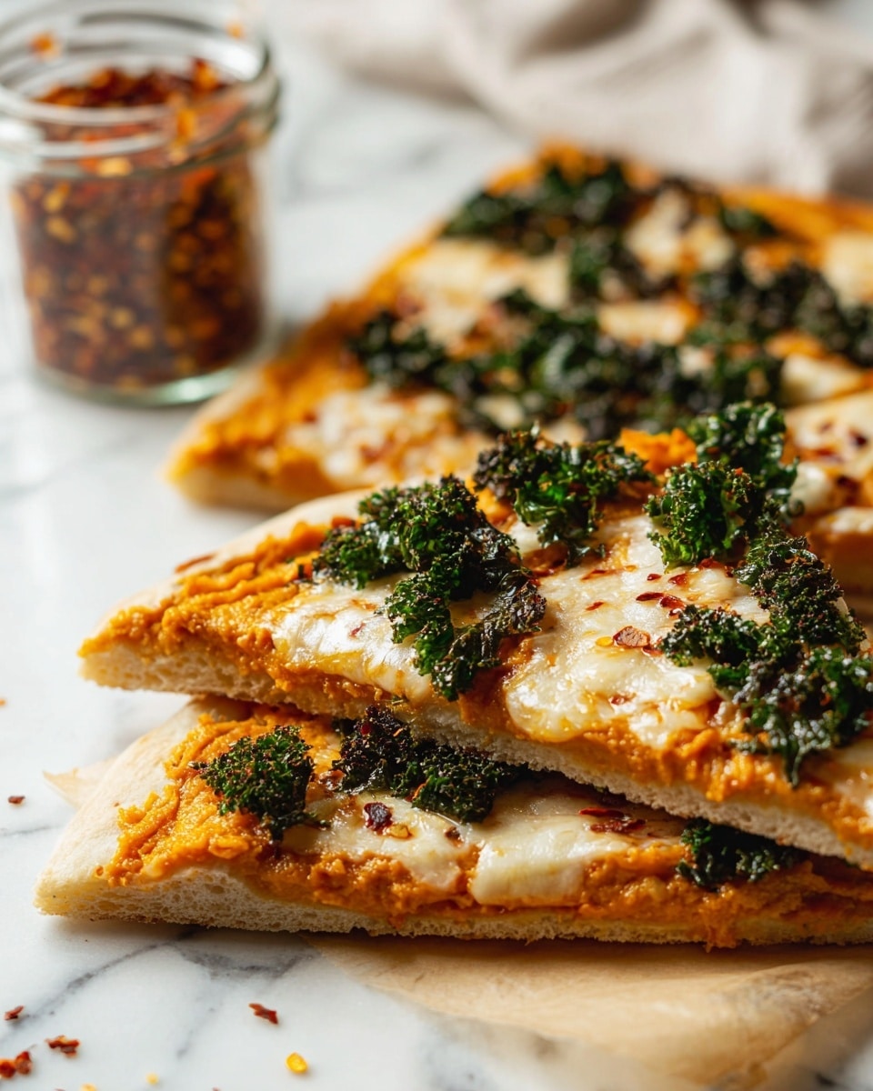 The image shows three slices of pizza stacked on a white marbled surface. The pizza has a light golden crust base topped with a layer of orange spread, likely a type of sauce or puree. Above this is a melted creamy white cheese layer that appears soft and smooth. Scattered on top are dark green crispy kale pieces adding texture and color contrast. In the background, a small glass jar filled with red chili flakes is slightly blurred. The scene is bright, with focus on the front slice, making the cheese and kale details very clear. Photo taken with an iphone --ar 4:5 --v 7