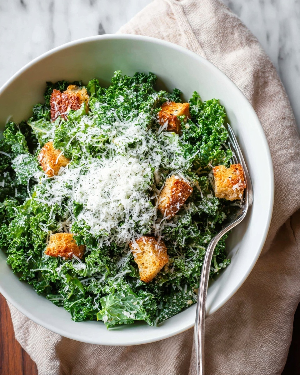 A white bowl holds a salad with three main layers. The bottom layer is dark green curly kale leaves. On top of the kale, there are several golden brown crunchy croutons scattered around. The final layer is a thick pile of finely grated white cheese that almost covers the kale and croutons. A silver fork rests on the edge of the bowl, and the bowl sits on a white marbled surface. photo taken with an iphone --ar 4:5 --v 7