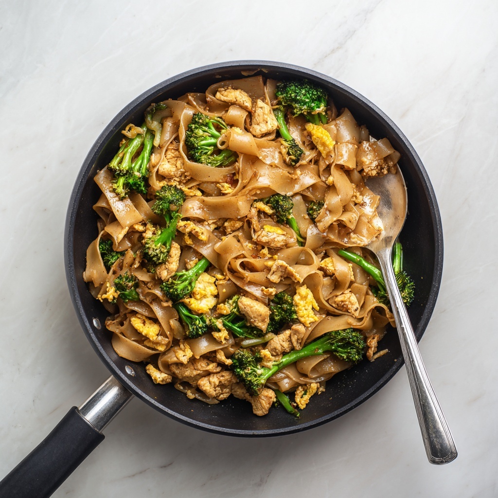 The image shows a black pan filled with a stir-fry dish. The dish has several layers: the bottom layer consists of wide, flat, light brown rice noodles with a slightly glossy texture. On top and mixed within are small green broccoli florets with a fresh, slightly crisp look. Scattered throughout are light golden pieces of scrambled eggs that have a soft texture. There are also pieces of cooked chicken, in light golden brown color, with a tender and juicy appearance. The ingredients are coated evenly with a shiny, dark brown sauce that gives them a rich, savory look. A shiny silver spoon is placed on the right side inside the pan, resting partially in the food. The pan sits on a white marbled surface. photo taken with an iphone --ar 4:5 --v 7