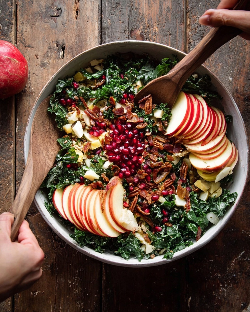 The dish is a fresh salad served in a white bowl filled with finely chopped dark green kale as the base layer. Thin slices of red and yellow apple are arranged in two neat clusters on opposite sides of the bowl, adding a bright red and pale yellow color contrast. Mixed throughout the salad are shiny red pomegranate seeds and small pieces of pale white cheese, scattered evenly on top. There are also bits of golden brown toasted seeds and small chunks of crispy brown bacon evenly spread across the bowl. A woman's hand holds the wooden salad spoon on one side, while another woman's hand uses a wooden spatula on the other, both partially visible, tossing the salad. The bowl is placed on a rustic wooden surface. Photo taken with an iphone --ar 4:5 --v 7