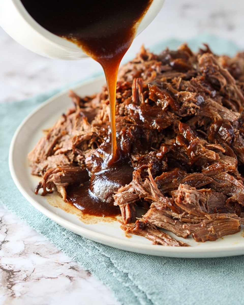 A white plate holds a large pile of shredded dark brown cooked meat with a mix of tender and slightly crispy edges. A thick, dark brown sauce is being poured over the meat from above, creating a glossy wet texture on the meat beneath. The plate sits on a light blue cloth with a white marbled surface underneath. The photo is close up, focusing on the pouring sauce and the texture of the shredded meat photo taken with an iphone --ar 4:5 --v 7