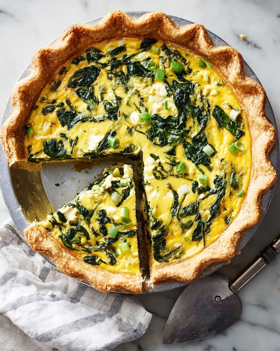The image shows a spinach quiche with a light golden crust that is thick and flaky, forming the bottom and edges. The filling has two main layers: the first is a creamy, pale yellow egg mixture that holds the quiche together, and the second, sitting on top of the egg layer, is a generous amount of cooked dark green spinach and small white cheese pieces scattered evenly. The quiche is in a round metal pan, with one slice removed and placed slightly outward, showing the different textures and layers inside. The pan is set on a white marbled surface with some crumbs around, and near it is a striped cloth and a metal pie server. Photo taken with an iphone --ar 4:5 --v 7