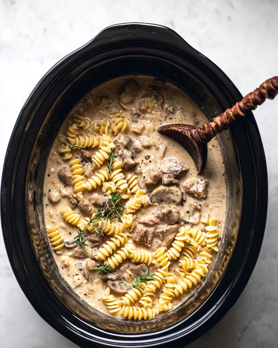 The image shows a white shallow bowl filled with a creamy pasta dish featuring short, curly pasta noodles in a light brown sauce. Mixed in are small chunks of tender-looking beef, coated in the same creamy sauce. The dish is topped with a sprinkle of ground black pepper and garnished with small green thyme sprigs placed on top. A vintage-style fork with a textured handle rests on the left side of the bowl, partly into the pasta. The bowl is placed on a white marbled surface, and the lighting is soft, highlighting the creamy texture and warm colors of the dish. Photo taken with an iphone --ar 4:5 --v 7