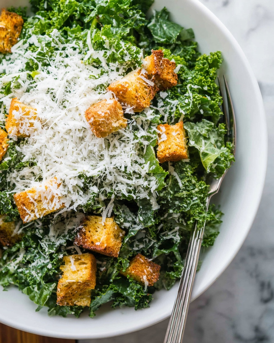 A large white bowl holds a fresh kale salad with dark green, curly leaves as the base layer, covered in creamy dressing that adds a slight gloss. Scattered on top are golden-brown crunchy croutons, adding texture and warm color contrast. The whole salad is topped with finely grated white cheese, lightly covering the top and giving a soft, powdery look. The bowl sits on a beige cloth on a white marbled surface. Photo taken with an iphone --ar 4:5 --v 7