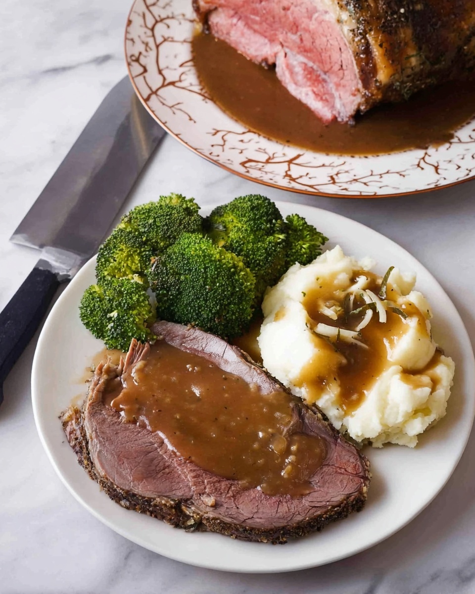 A white plate holds a meal with three parts: on the bottom left, there is a large slice of dark brown roast beef covered with thick brown gravy; to the upper left, there are several bright green broccoli florets with small bits of melted butter on top; on the right side, there is a round scoop of creamy white mashed potatoes also topped with brown gravy. In the background on a separate white plate with a subtle brown decorative pattern, a large piece of roast beef shows a pink center and a dark seasoned crust. A large knife with a black handle rests on a white marbled surface beside the plates. Photo taken with an iphone --ar 4:5 --v 7