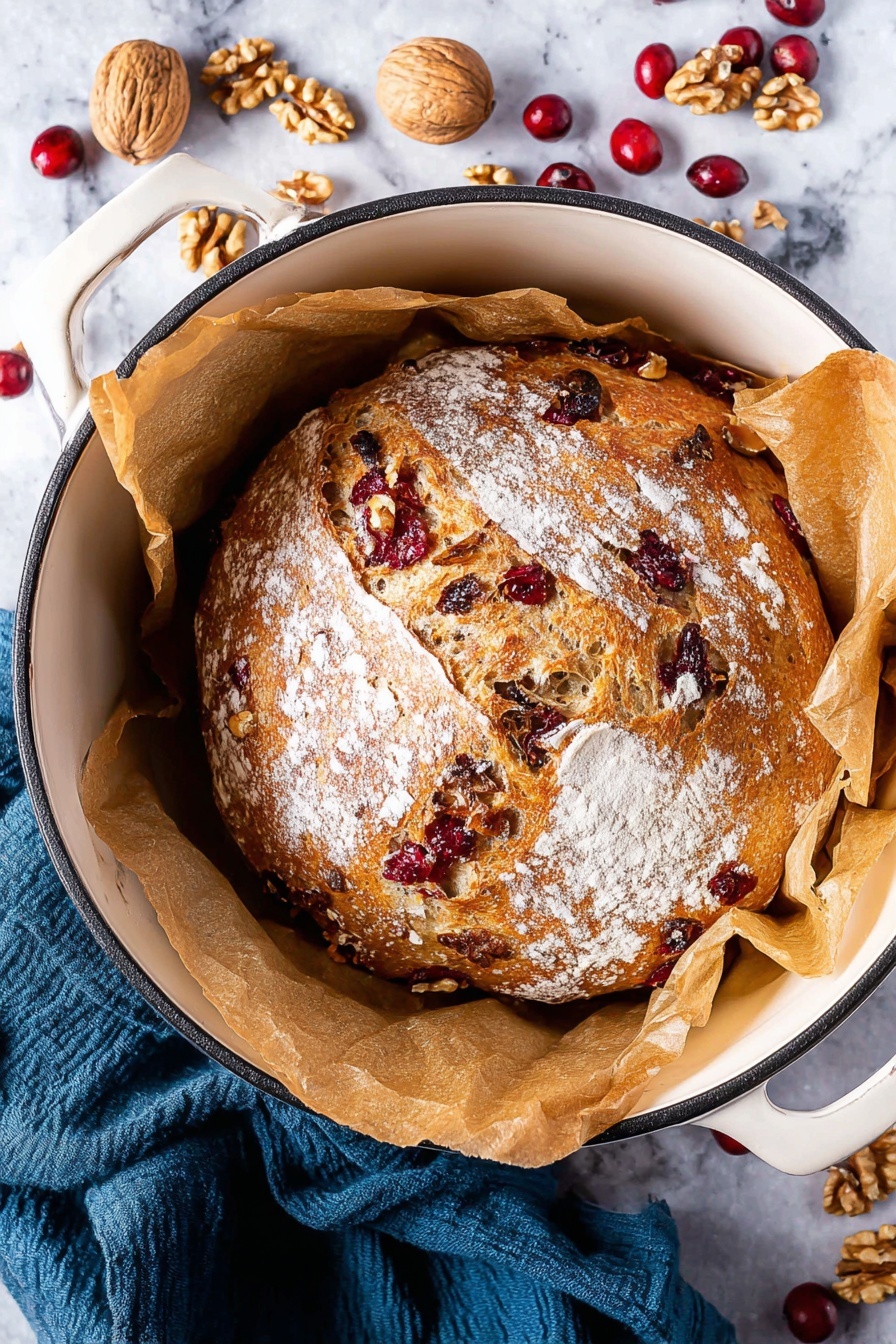 A close-up image shows two thick slices of bread placed on a wooden board against a white marbled texture background. The bread has a golden-brown crust and a light beige inside filled with visible pieces of red cranberries and light brown walnuts spread evenly throughout. The texture looks soft with small holes in the crumb. In the top left corner of the image, there are some walnut pieces and dried cranberries scattered on the wooden board. A dark gray cloth is also partly visible in the upper right area. photo taken with an iphone --ar 2:3 --v 7 - No-Knead Cranberry Walnut Bread, easy holiday bread, festive cranberry walnut loaf, no knead bread recipe, cranberry walnut bread instructions