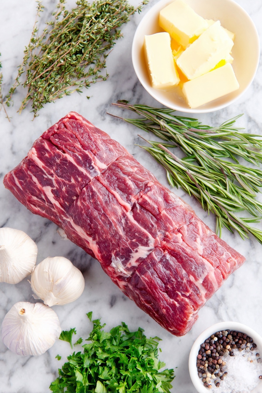 Flat lay of a whole trimmed beef tenderloin roast with a rich red color and fine marbling, three whole uncracked garlic cloves with smooth white skins, a small heap of fresh flat-leaf parsley sprigs, fresh rosemary sprigs with needle-like leaves, fresh oregano sprigs with small green leaves, a few whole black peppercorns scattered naturally, a small white ceramic bowl holding softened pale yellow butter, a small white bowl with dark glossy balsamic vinegar, a small white bowl of thick Worcestershire sauce with a deep brown hue, and a small pile of coarse sea salt crystals, all arranged symmetrically with perfect balance, placed on a clean white marble surface, soft natural light, photo taken with an iPhone, professional food photography style, fresh ingredients, white ceramic bowls, no bottles, no duplicates, no utensils, no packaging --ar 2:3 --v 7 --p m7354615311229779997 - Oven-Roasted Beef Tenderloin with Garlic Butter, beef tenderloin dinner ideas, elegant beef recipes, juicy roasted beef, garlic butter beef main dish