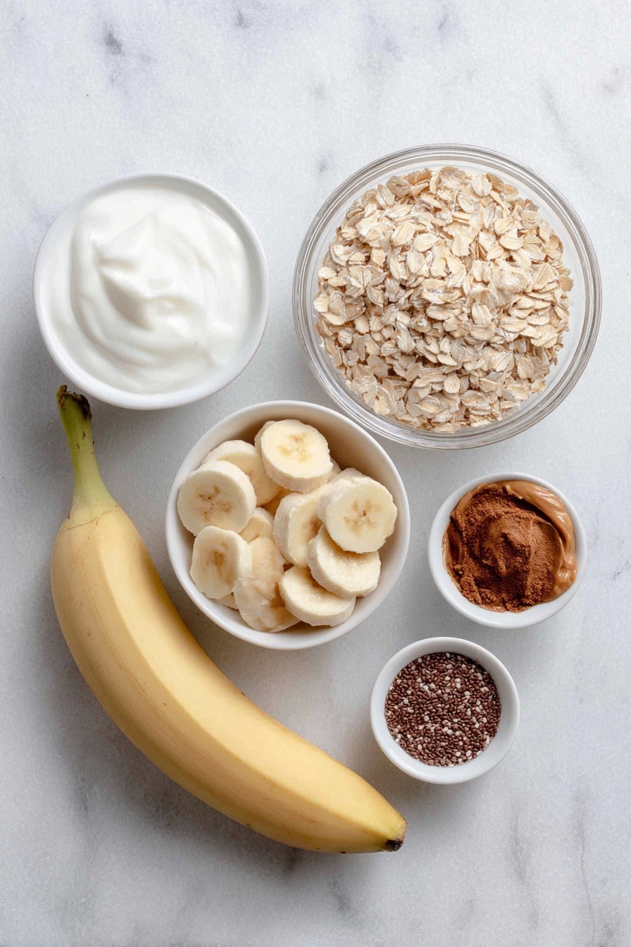 Flat lay of a large ripe banana, several fresh banana slices arranged neatly, a small white bowl of creamy vanilla yogurt, a small white bowl of rolled gluten-free oats, a small white bowl of smooth peanut butter, a small white bowl of almond milk, a small white bowl of chia seeds, a small white bowl of ground cinnamon, placed on a clean white marble surface, soft natural light, photo taken with an iPhone, professional food photography style, fresh ingredients, white ceramic bowls, no bottles, no duplicates, no utensils, no packaging --ar 2:3 --v 7 --p m7354615311229779997 - High Protein Peanut Butter Banana Overnight Oats, healthy overnight oats with peanut butter, easy protein breakfast recipes, high-protein oats for weight loss, delicious banana oats