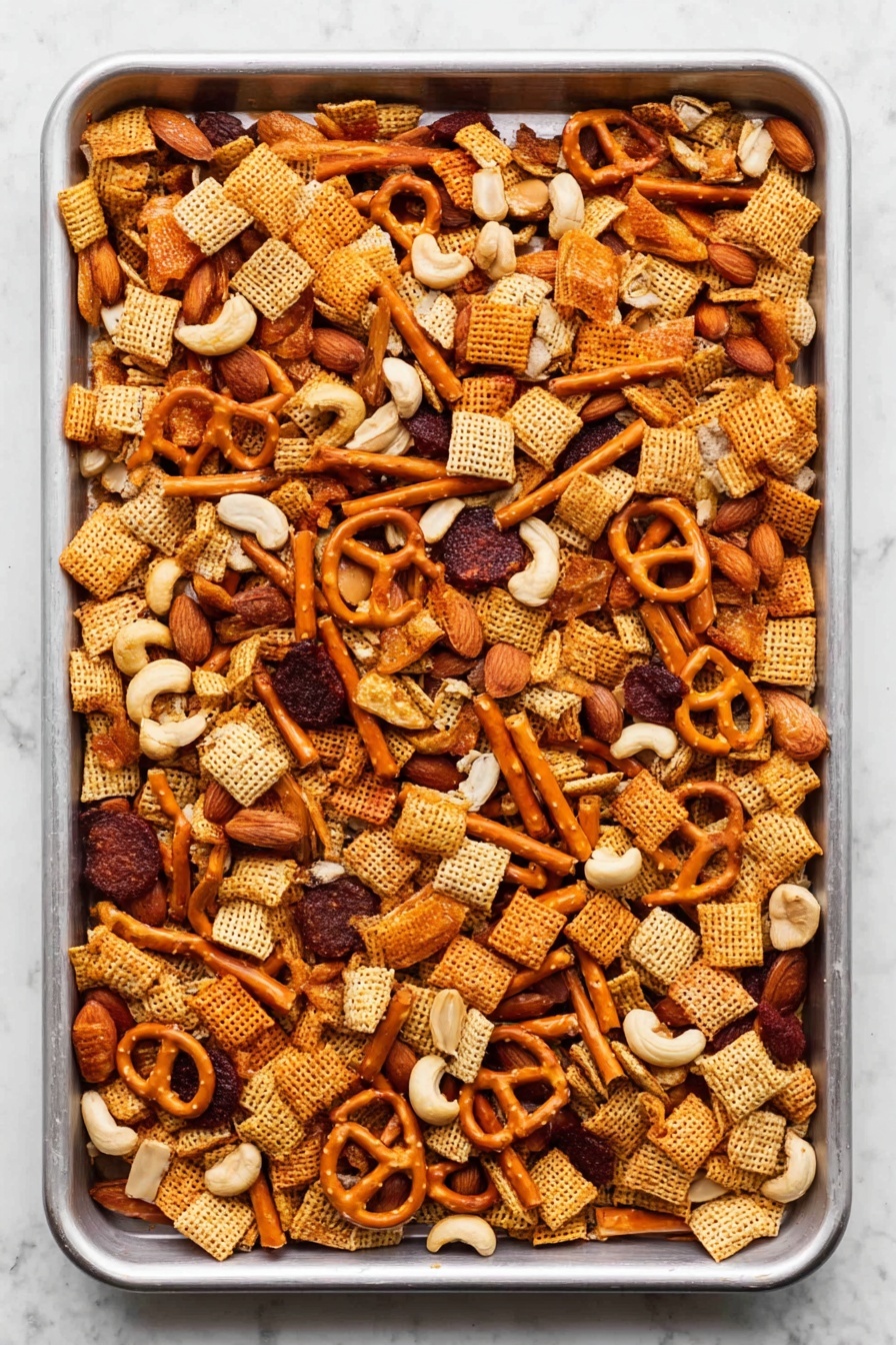 A large white baking tray filled with a mixed snack party food laid out evenly. The mix has small square cereal pieces in light brown, round dark reddish-brown slices, small orange pretzels, light orange stick-shaped crackers, off-white cashew nuts, and a few whole almonds scattered on top. All pieces have a crunchy texture, and the tray rests on a white marbled surface. Photo taken with an iphone --ar 2:3 --v 7 - Sweet and Spicy Chex Mix, Chex Mix recipe, spicy snack mix, crunchy sweet and spicy snack, homemade Chex Mix