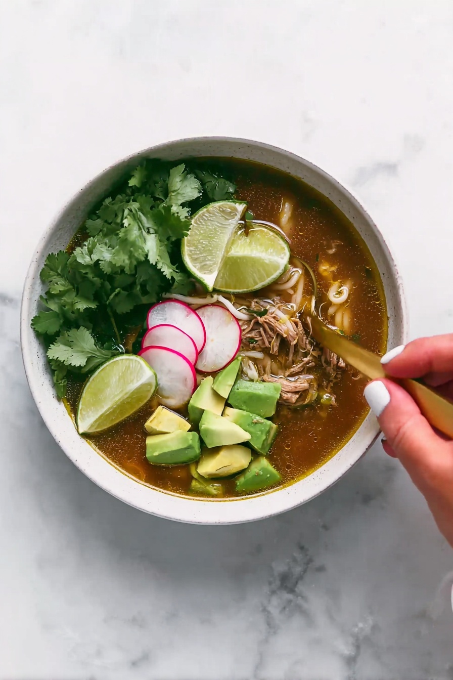 A white bowl filled with soup that has a brownish broth at the bottom layer mixed with pieces of shredded meat and small white noodles. On top of the soup, there are bright green chunks of avocado stacked on one side and thin slices of radish with a pale pink color beside them. Fresh green cilantro leaves are also scattered over the soup. A gold spoon is placed inside the bowl, partially submerged in the broth. Above the bowl, a woman's hand holding a lime wedge is about to squeeze it into the soup. The surface beneath the bowl is a white marbled texture. photo taken with an iphone --ar 2:3 --v 7 - Slow Cooker Chicken Posole Verde, Chicken Posole Verde recipe, Mexican green chicken soup, easy slow cooker Mexican dishes, healthy chicken stew