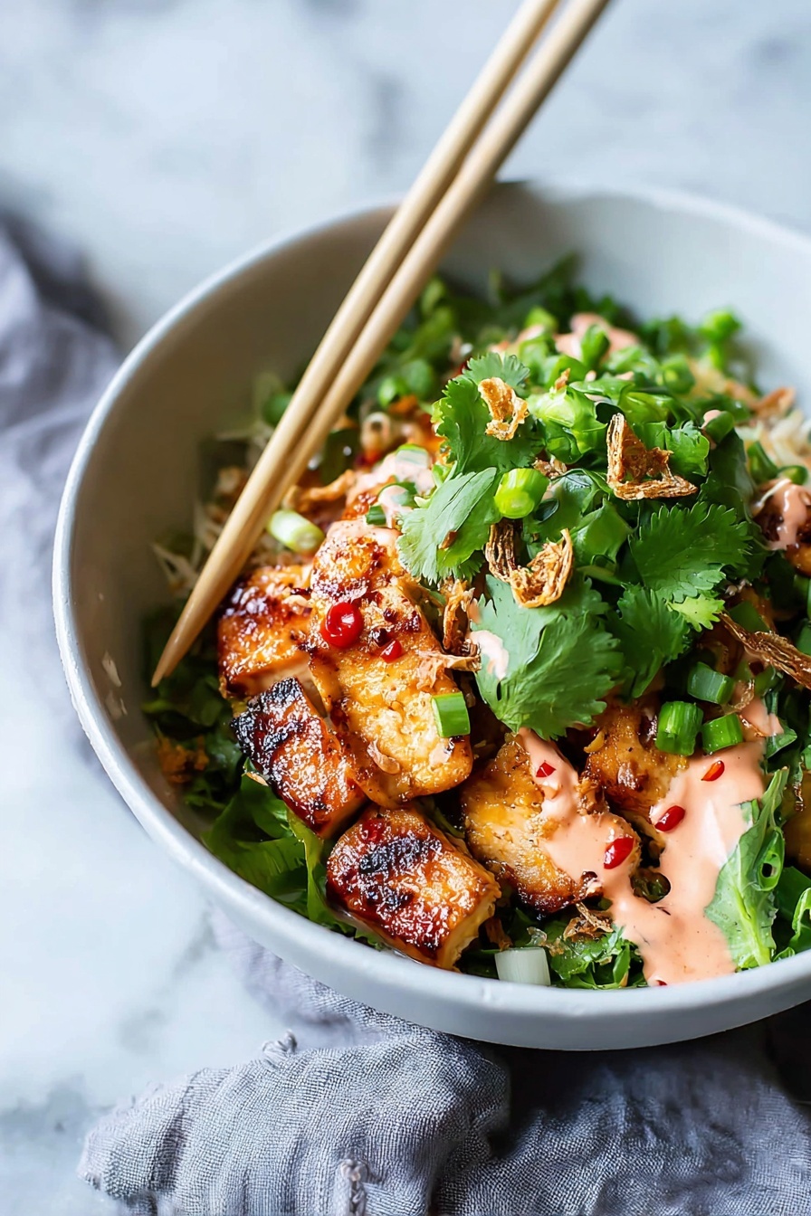 A white bowl holds a colorful dish with several layers starting with golden-brown grilled chicken pieces that have a shiny glaze with small red chili spots, placed at the bottom. On top there is a generous layer of fresh, bright green cilantro leaves and chopped green onions, adding a fresh texture. Some crispy fried shallots are scattered over the greens, and drizzled in spots is a light pink creamy sauce. A pair of light wood chopsticks rest on the rim of the bowl, angled over the food. The bowl sits on a white marbled surface with a soft gray cloth partly visible beside it. Photo taken with an iphone --ar 2:3 --v 7 - Sticky Glazed Tofu Bowl with Yum Yum Sauce, plant-based tofu bowl recipes, spicy sweet tofu dishes, vegan glaze tofu recipes, easy tofu dinner ideas