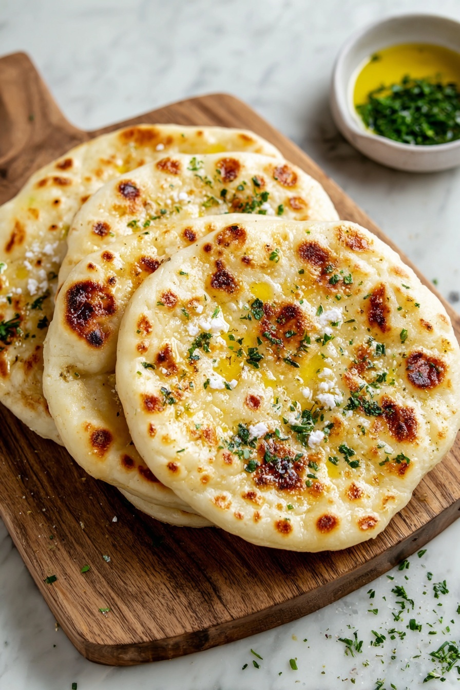 Four flat round breads with golden brown spots lay stacked on a wooden board, each topped with melted butter and small bits of white cheese sprinkled with chopped green herbs. The wooden board sits on a white marbled surface, with a small bowl of oil and some scattered herbs nearby. photo taken with an iphone --ar 2:3 --v 7 - Cottage Cheese Flatbread, easy flatbread recipes, quick homemade flatbread, healthy flatbread ideas, soft flatbread with cottage cheese