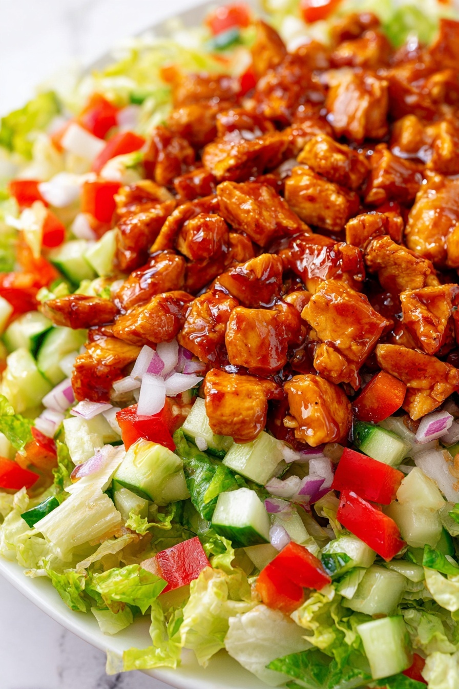 The dish shows a close-up of a salad on a white plate with a white marbled background. The bottom layer has bright green chopped lettuce with a light, crisp texture. Over the lettuce, there are small diced pieces of red bell pepper and white chopped onion spread evenly, adding red and white colors. There are also small cubes of green cucumber scattered throughout this layer. Finally, the top layer consists of chunks of chicken coated in a shiny reddish-brown sauce, giving the salad a rich, glazed look. Photo taken with an iphone --ar 2:3 --v 7 - Honey Hot Chicken Salad, spicy chicken salad with honey, quick chicken salad recipe, buffalo chicken salad, sweet and spicy chicken salad
